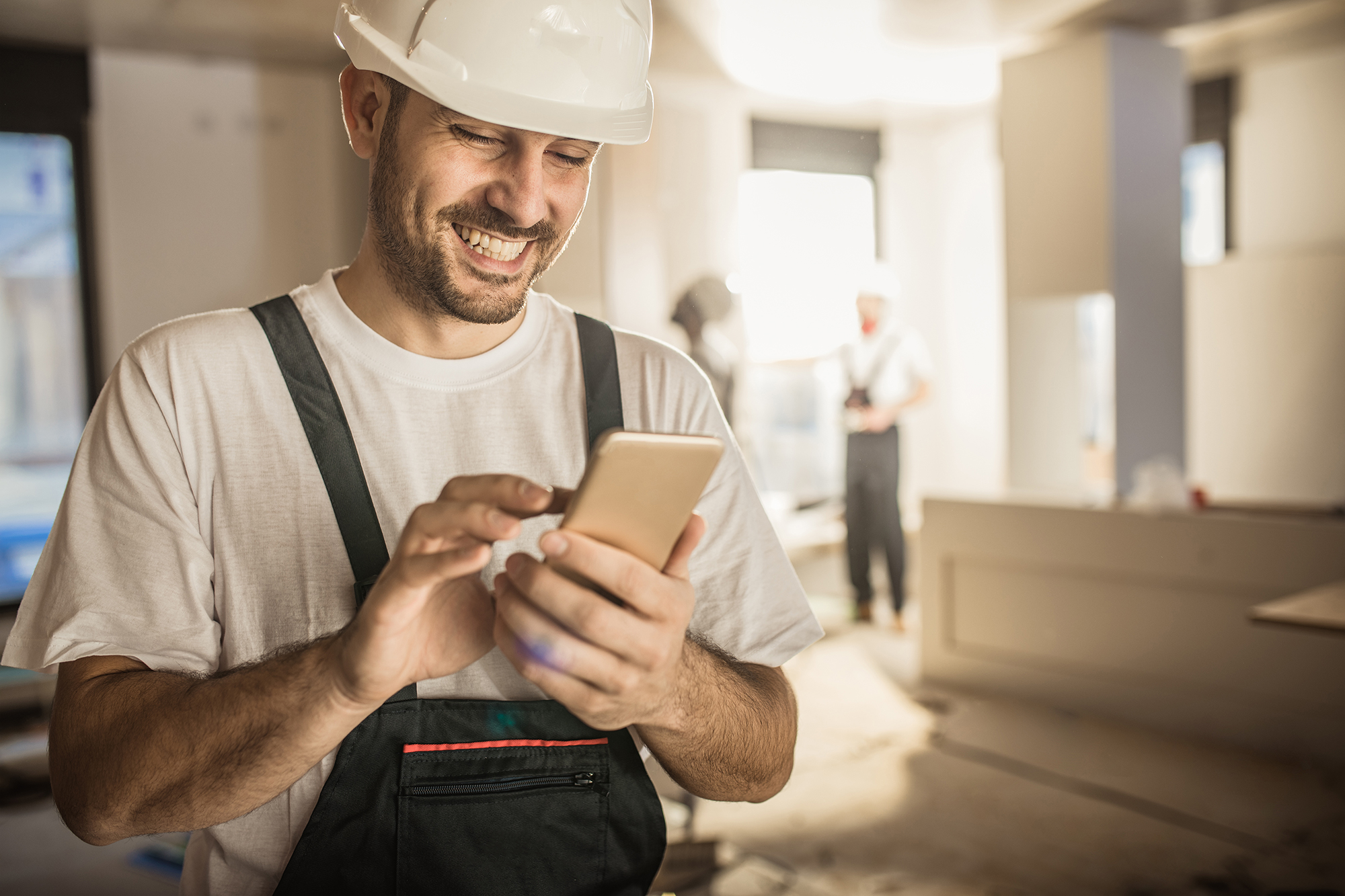 Handwerker nutzt Smartphone auf Baustelle – Symbol für digitale Lösungen und effiziente Projektabwicklung über die directpool Plattform.