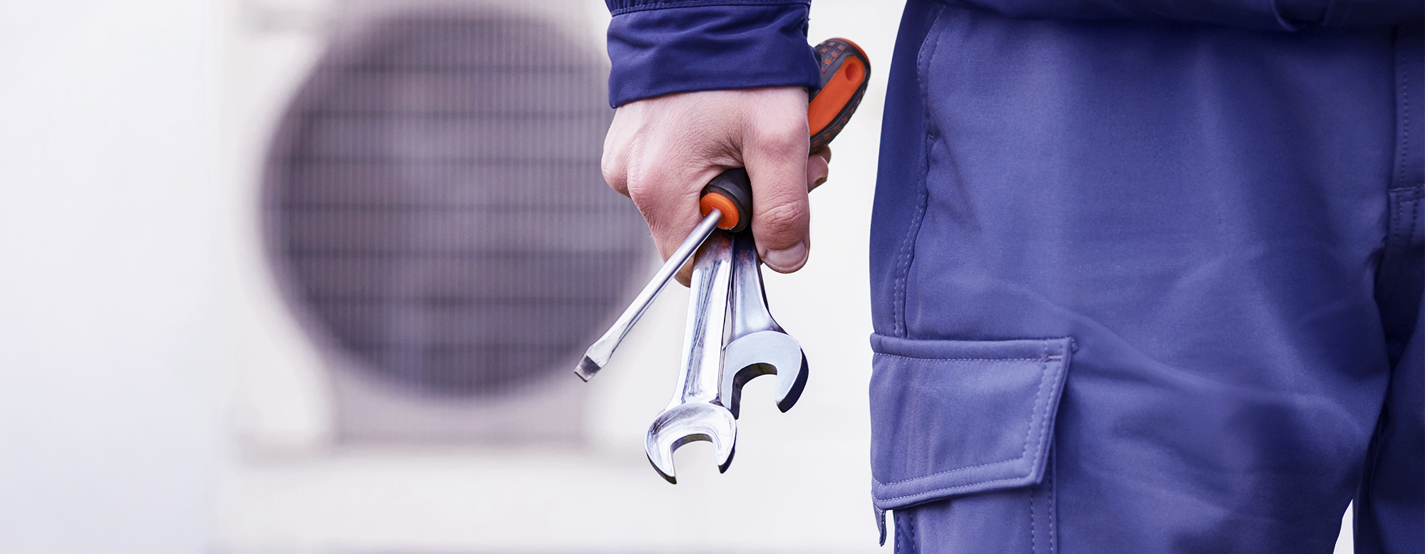 Handwerker hält Werkzeuge vor Wärmepumpe – Symbol für praxisnahe Lösungen und effiziente Projektabwicklung über die directpool Plattform.