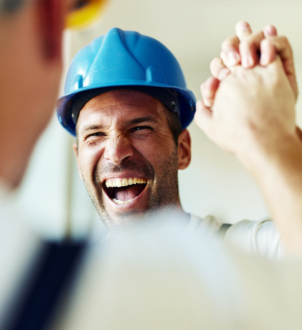 Zufriedener Handwerker mit Schutzhelm gibt Kollegen High-Five – Symbol für erfolgreiche Zusammenarbeit mit unabhängigen Energieberatern im Förderprozess von directpool.